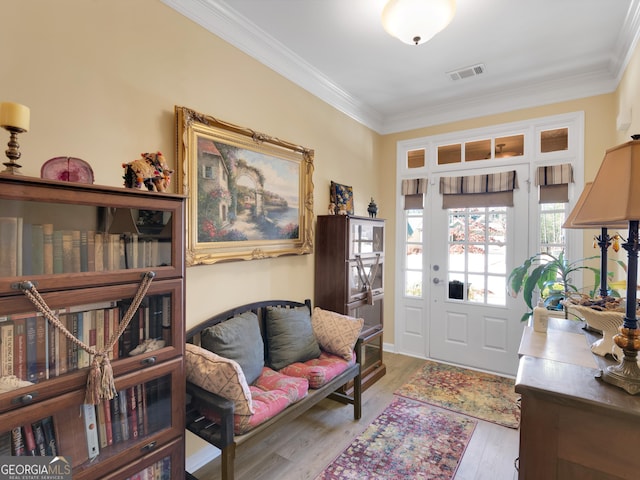 entrance foyer featuring crown molding, visible vents, and wood finished floors