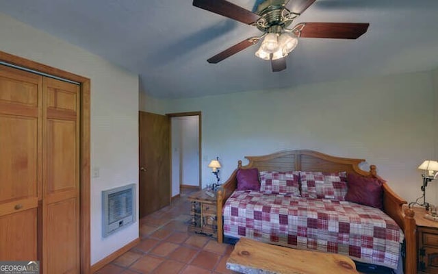 bedroom with heating unit, tile patterned flooring, baseboards, and ceiling fan