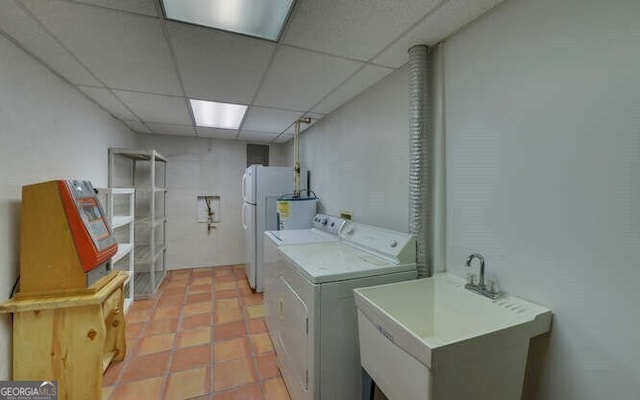clothes washing area with washing machine and dryer, water heater, a sink, and light tile patterned floors