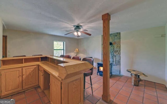 kitchen with light tile patterned floors, open floor plan, a breakfast bar area, and ceiling fan