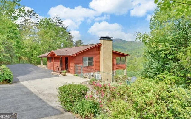view of front of home with a chimney, a mountain view, and concrete driveway