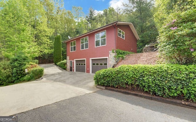 view of side of property with aphalt driveway and a garage