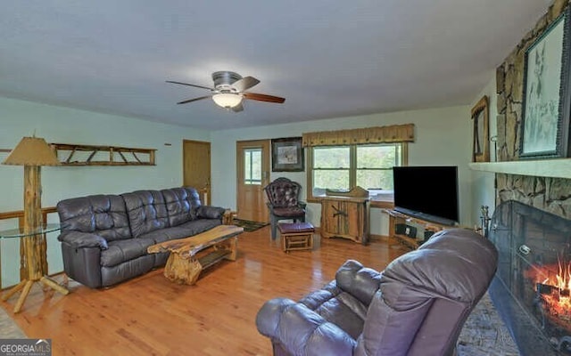 living room featuring wood finished floors, a fireplace, and ceiling fan