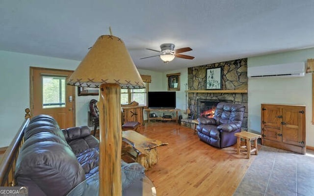 living room featuring ceiling fan, wood finished floors, a fireplace, and a wall mounted AC