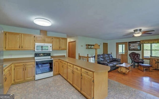 kitchen with light countertops, light brown cabinets, range with electric stovetop, and white microwave