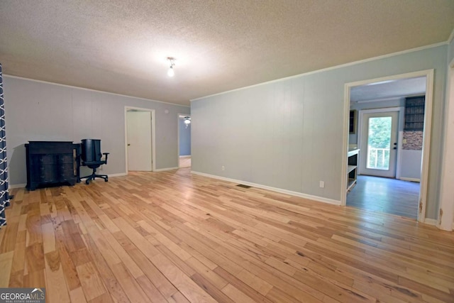 unfurnished living room with a textured ceiling, light wood-type flooring, visible vents, crown molding, and baseboards