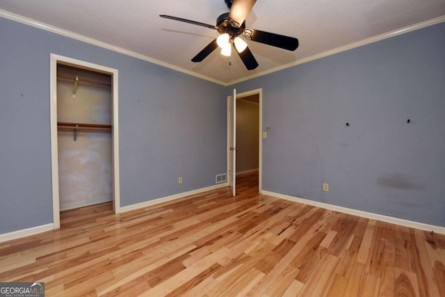 unfurnished bedroom with a closet, visible vents, wood finished floors, and crown molding