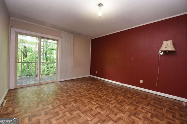 empty room with crown molding, a textured ceiling, baseboards, and wood walls