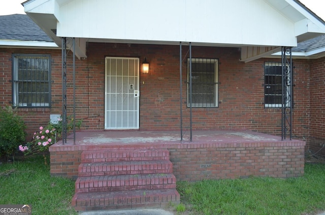 entrance to property featuring brick siding and covered porch