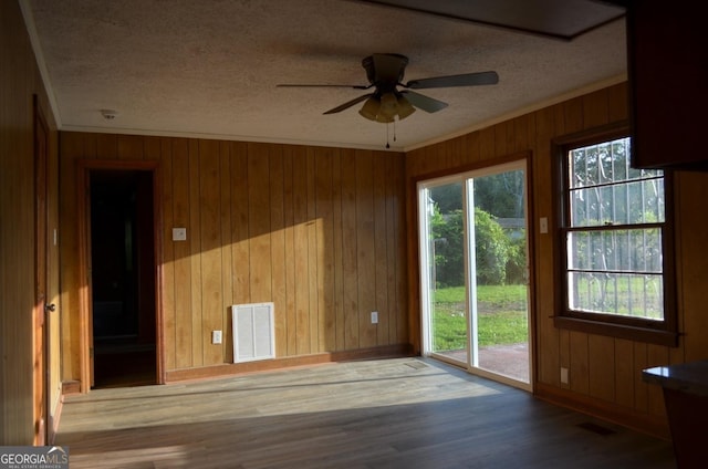 spare room featuring a healthy amount of sunlight, ornamental molding, and visible vents