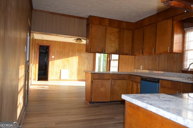 kitchen featuring wooden walls, brown cabinets, plenty of natural light, and dishwasher