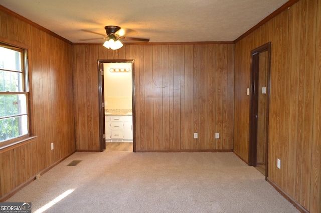 unfurnished room with ceiling fan, wood walls, and light colored carpet