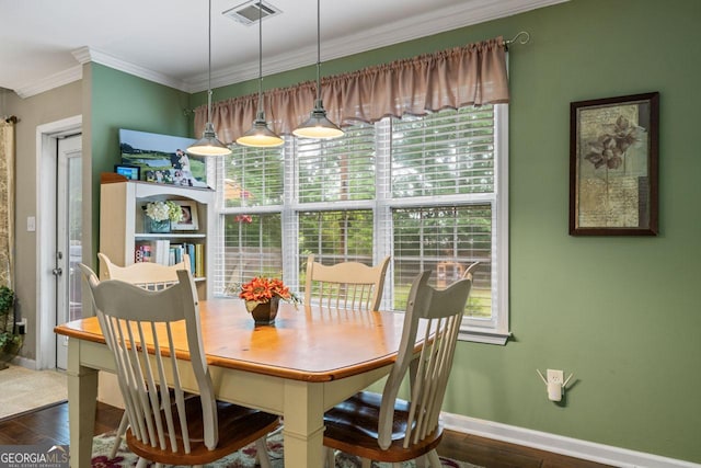 dining area with baseboards, crown molding, visible vents, and wood finished floors