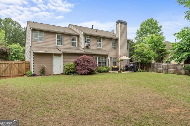 rear view of house with a fenced backyard, a yard, and a chimney