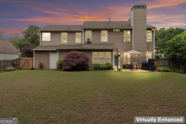 rear view of house with a yard, a chimney, a patio, and a fenced backyard