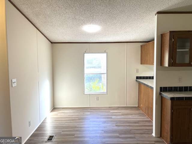 104 Scattered Pines Rd, Hortense, GA 31543 - kitchen featuring a textured ceiling, light wood finished floors, crown molding, and brown cabinetry