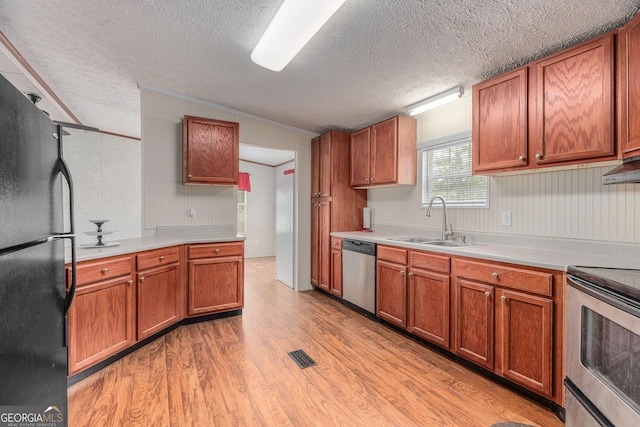 kitchen featuring light wood-style floors, light countertops, appliances with stainless steel finishes, and a sink