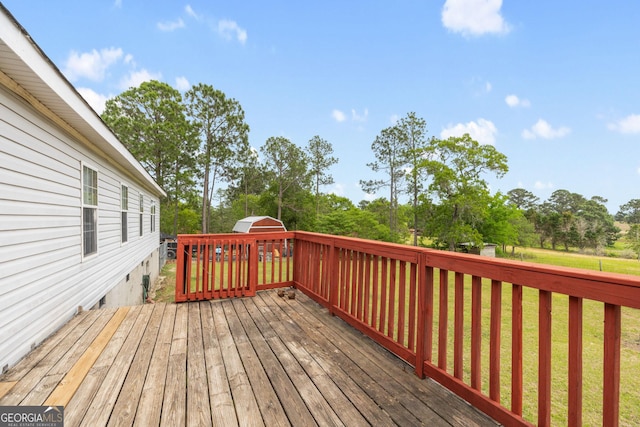 deck with a yard, an outdoor structure, and a storage shed