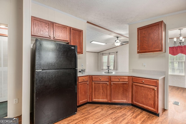 kitchen featuring ceiling fan with notable chandelier, freestanding refrigerator, a textured ceiling, light countertops, and light wood-style floors