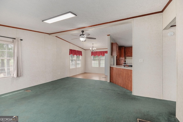 unfurnished living room with a textured ceiling, ceiling fan with notable chandelier, ornamental molding, and carpet floors