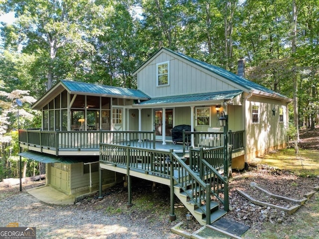 back of property with a chimney, metal roof, a sunroom, and board and batten siding