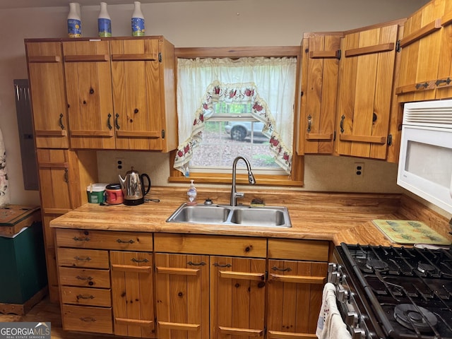 kitchen featuring light countertops, brown cabinetry, white microwave, and a sink