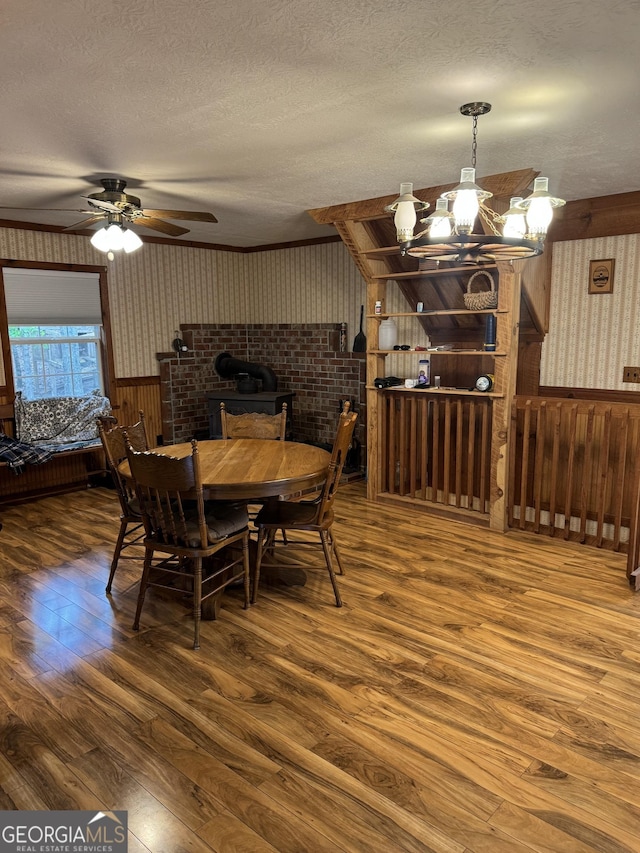dining space featuring wood-type flooring, wallpapered walls, a wainscoted wall, a textured ceiling, and wooden walls