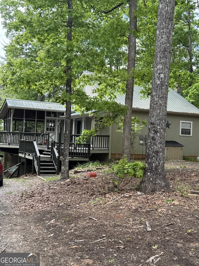 rear view of house featuring a sunroom, a deck, and metal roof
