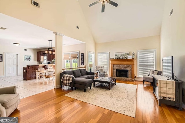 595 Mcgarity Dr, Mcdonough, GA 30252 - living room featuring a brick fireplace, visible vents, ceiling fan, and high vaulted ceiling