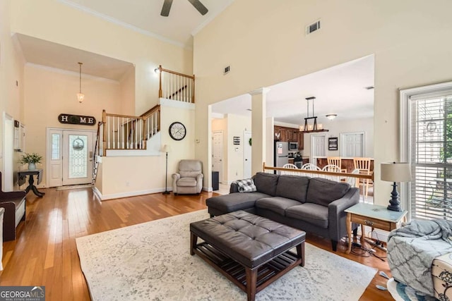 595 Mcgarity Dr, Mcdonough, GA 30252 - living area featuring ornamental molding, a towering ceiling, visible vents, stairway, and ceiling fan