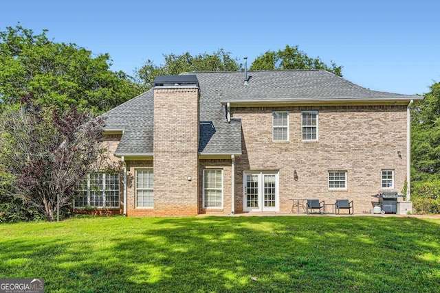 595 Mcgarity Dr, Mcdonough, GA 30252 - back of property featuring a lawn, a chimney, brick siding, and roof with shingles
