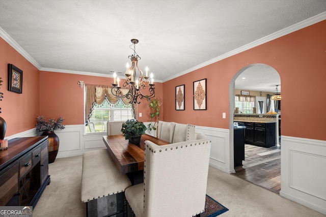 dining room featuring a chandelier, wainscoting, arched walkways, and light carpet