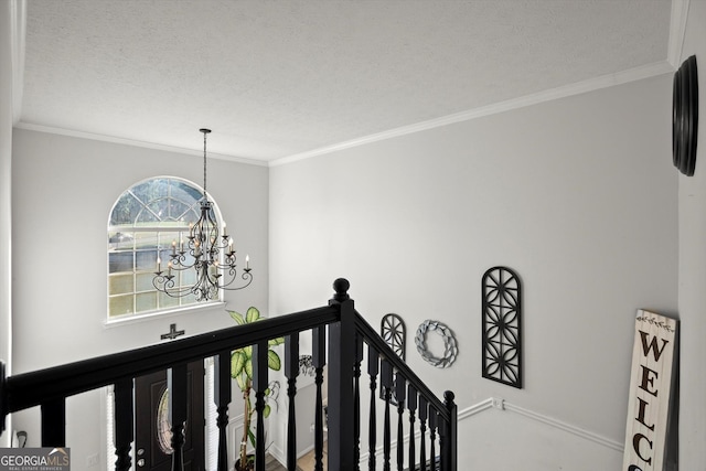 stairs with an inviting chandelier, a textured ceiling, baseboards, and crown molding