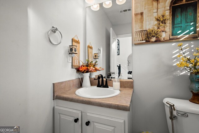 bathroom with toilet, visible vents, and vanity