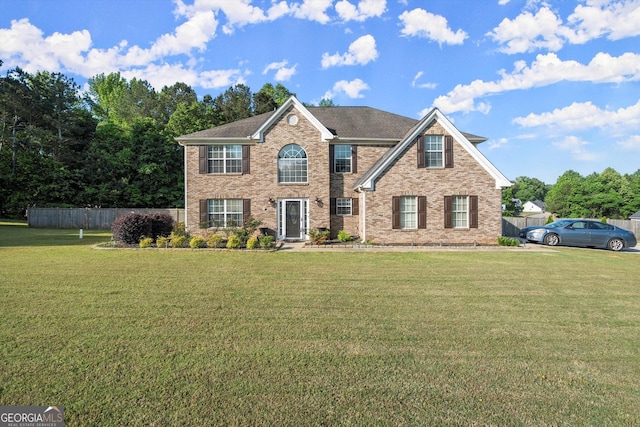 view of front of home featuring brick siding, fence, and a front yard