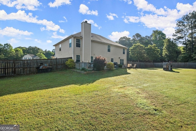 exterior space with a fenced backyard, a chimney, and a lawn