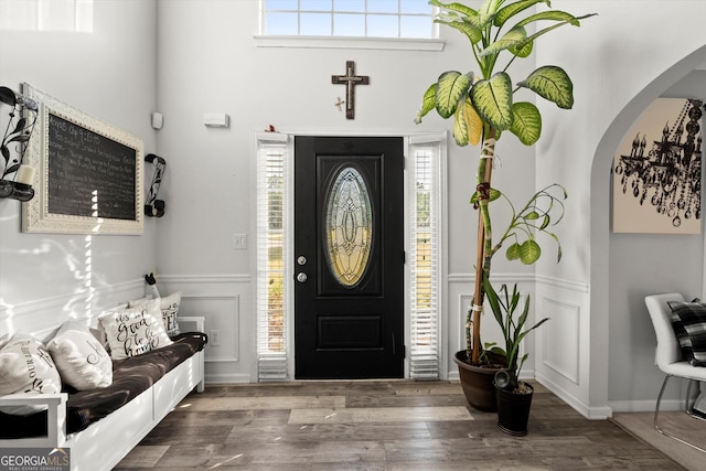 entryway featuring a decorative wall, arched walkways, a wainscoted wall, and plenty of natural light