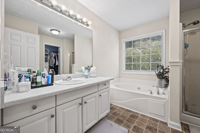 173 Kingswood Dr, Ellenwood, GA 30294 - full bathroom with vanity, a textured ceiling, a stall shower, a walk in closet, and a garden tub