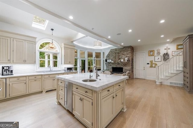 4500 Candacraig, Alpharetta, GA 30022 - kitchen featuring cream cabinets, a fireplace, a skylight, open floor plan, and light wood-style floors