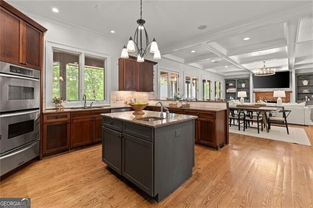 4290 Bobbins Way, Cumming, GA 30041 - kitchen with a chandelier, stainless steel double oven, a warming drawer, an island with sink, and light wood finished floors