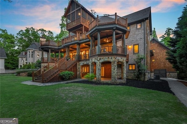 4290 Bobbins Way, Cumming, GA 30041 - back of house at dusk featuring a balcony, stone siding, a lawn, and stairs