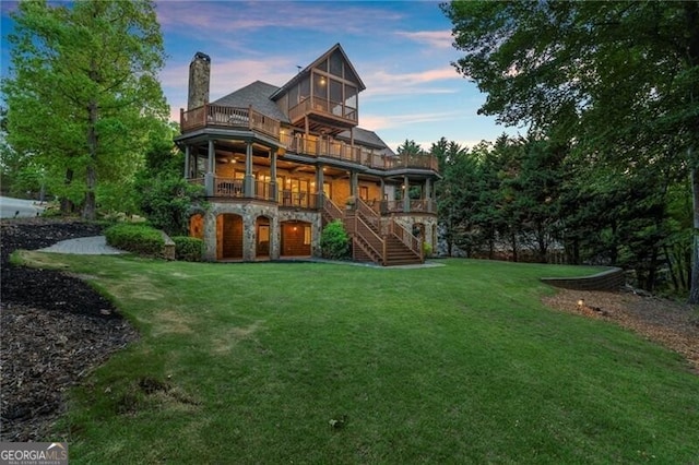 4290 Bobbins Way, Cumming, GA 30041 - back of property at dusk featuring a balcony, a lawn, stairs, and stone siding