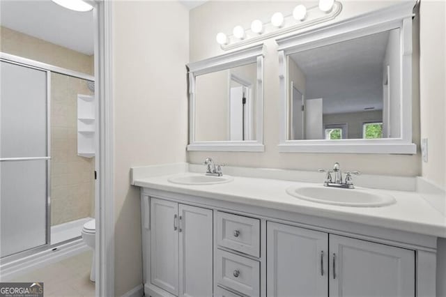 full bathroom featuring toilet, a stall shower, double vanity, and tile patterned flooring