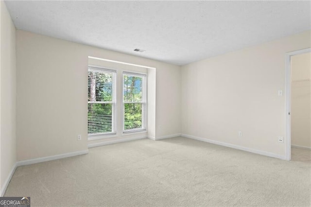 carpeted empty room with baseboards and a textured ceiling