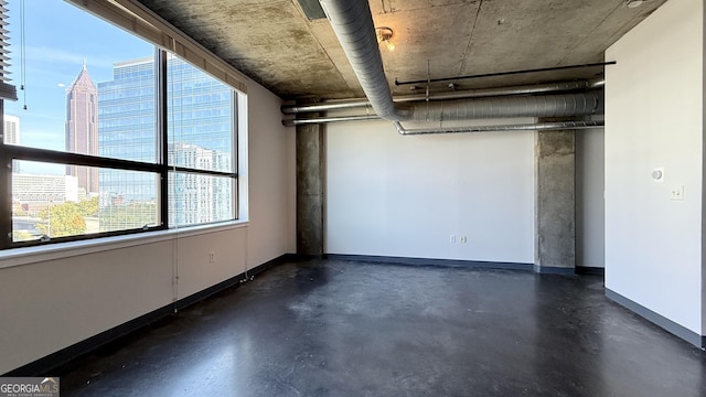 interior space featuring a city view, concrete flooring, and baseboards