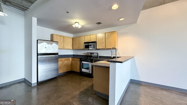 kitchen featuring a peninsula, concrete flooring, baseboards, and appliances with stainless steel finishes