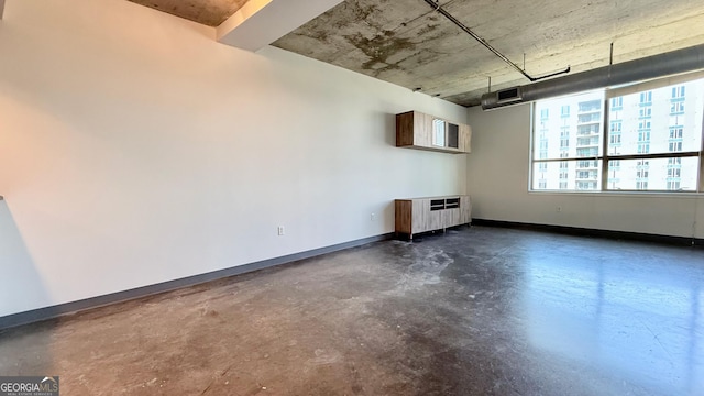 empty room featuring concrete flooring, baseboards, and radiator heating unit