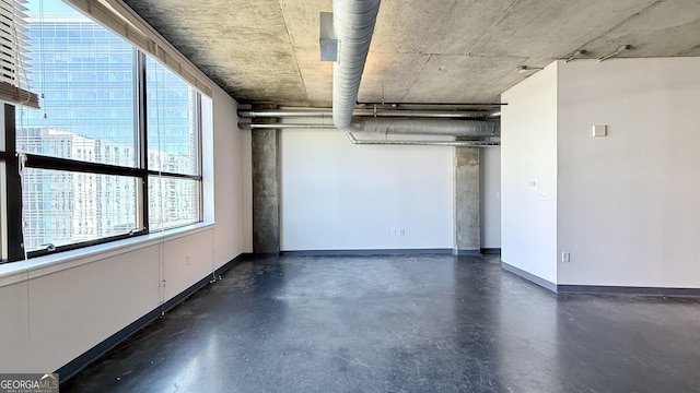 unfurnished room featuring finished concrete flooring and baseboards