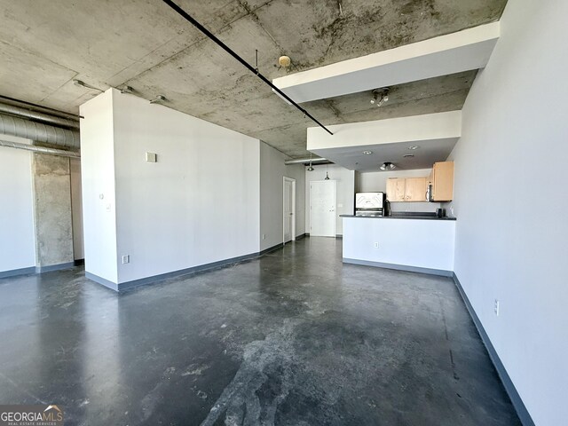 unfurnished living room with finished concrete flooring and baseboards