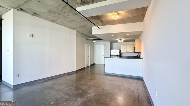 unfurnished living room featuring baseboards and finished concrete flooring